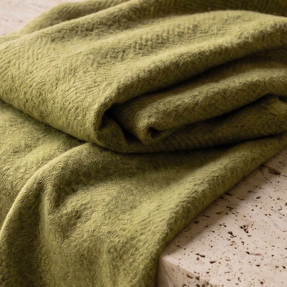 Olive alpaca scarf folded on travertine